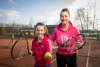 moeder en dochter in sportoutfits met tennisracket in handen op sportveld