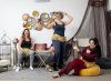 drie vrouwen met buikdanskleding in dansstudio waarvan een zittend met de duim omhoog, eentje aan dansend en eentje lachend in de achtergrond