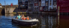 Gezin in opblaasboot - varend op een rivier met huizen in de achtergrond