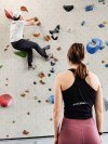 vrouw kijkt naar man die aan het boulderen is
