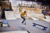 jongen op step springt over obstacle in skatehal
