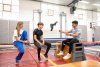 jongen en meisje zitten op een bank in een sportzaal. Zij luisteren naar de trainer.