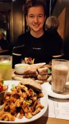 Koen zit aan tafel, op tafel twee volle borden met eten en drankjes.