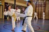 vrouw in karatepak kickt man in karatepack in sporthal