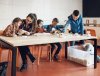 Vrouw en vier kinderen aan tafel bouwen met steentjes
