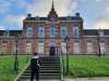 jongen staat op een trap voor een herenhuis