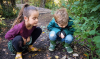 Twee kinderen kijken naar een paddenstoel