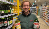 Man staat met twee flessen olijfolie in zijn hand in de supermarkt