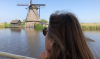 Vrouw kijkt naar een molen vanaf het water